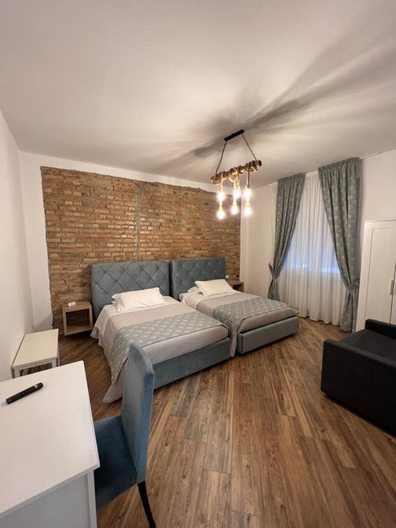 ein Schlafzimmer mit einem Bett und einer Ziegelwand in der Unterkunft Zelia Rooms in San Ferdinando