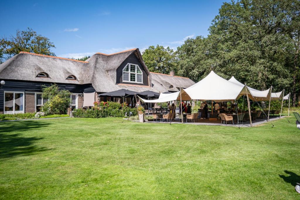 a house with tents in front of a yard at Landgoedhotel Woodbrooke Barchem in Barchem