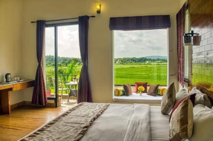 a bedroom with a large bed with a large window at Corbett Wild Nature View Resort in Rāmnagar