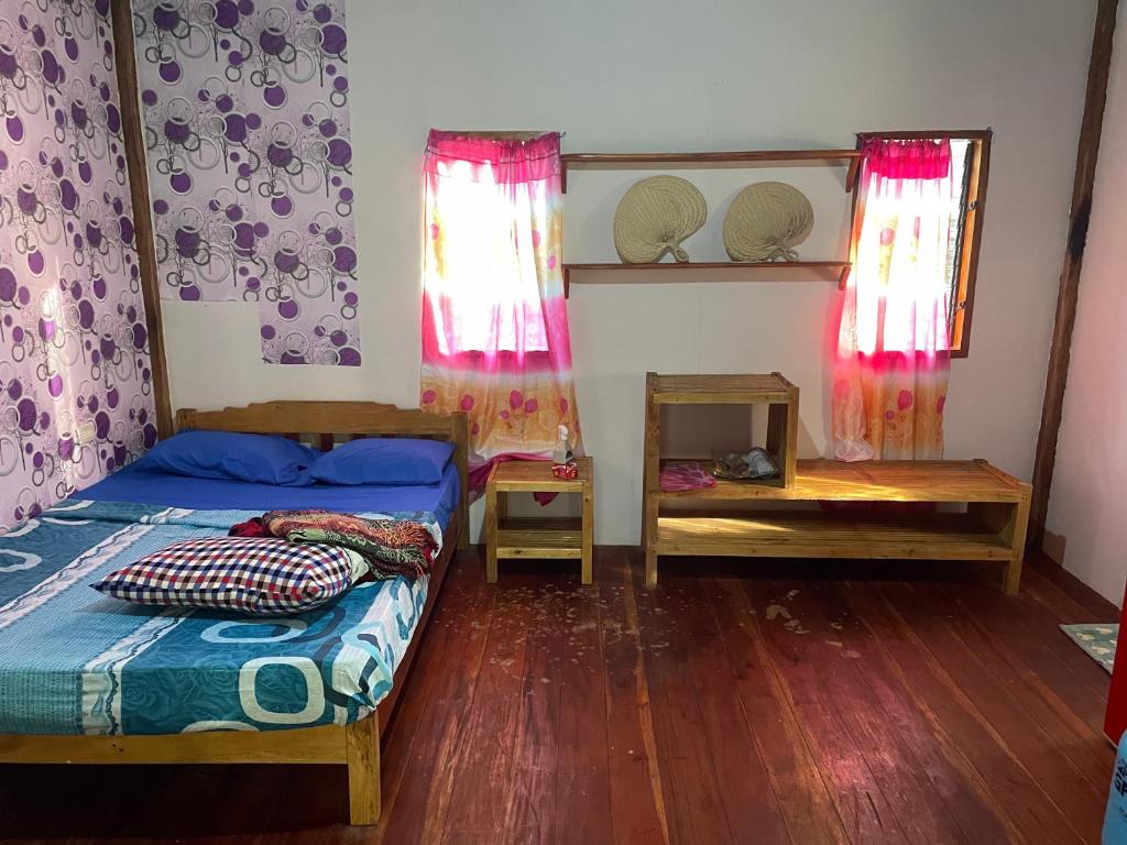 een slaapkamer met 2 bedden en houten vloeren en ramen bij Jermaine quiet house in Lazi