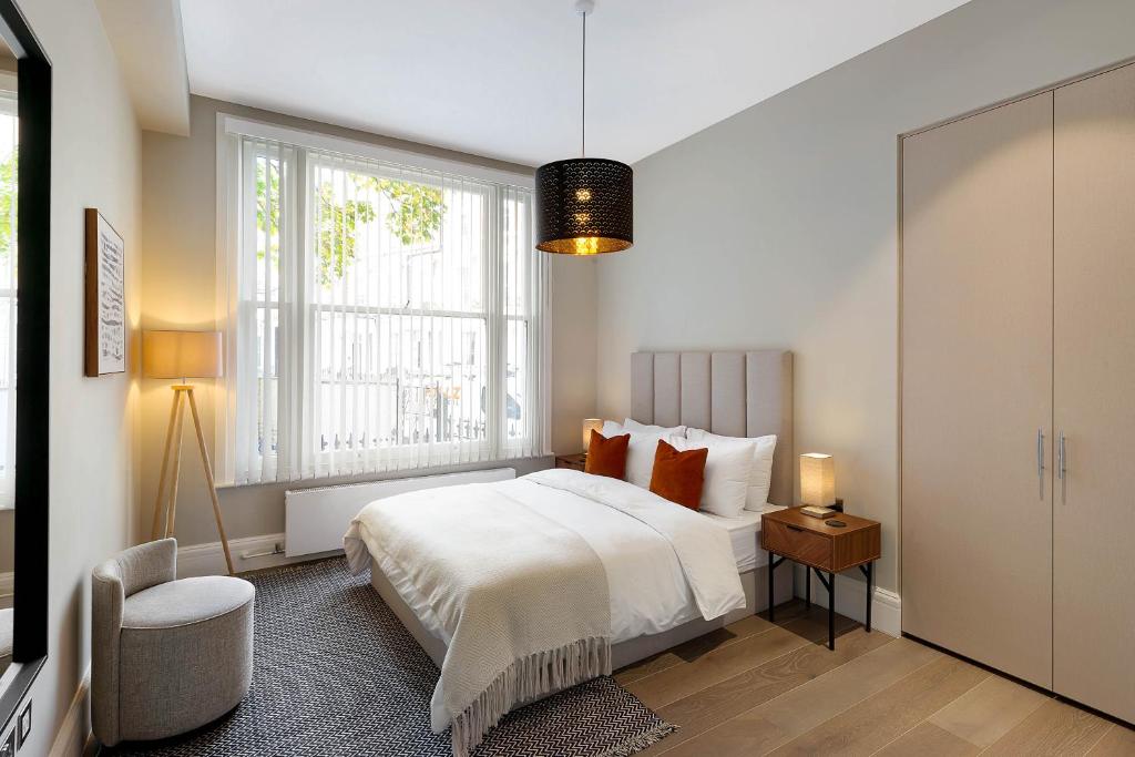 een slaapkamer met een wit bed en een raam bij Beautiful Serviced Apartment London in Londen