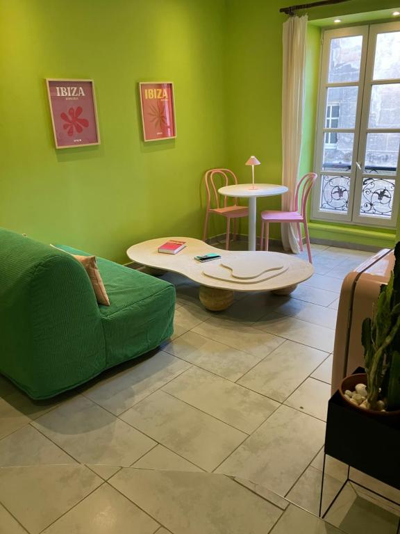 a green living room with a couch and a table at Appartement Ibiz’Arles in Arles
