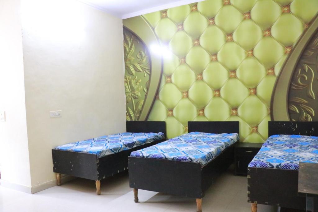 dwa łóżka w pokoju ze ścianą w obiekcie Tanmay Homes and PG w mieście Gurgaon