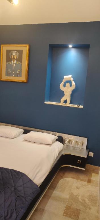 una camera da letto con una parete blu, un letto e una foto di Hotel Le Saint Julien a Saint-Julien-du-Sault