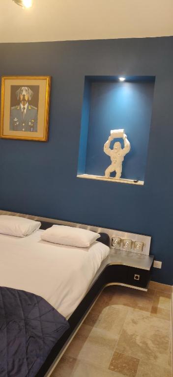 Un dormitorio con una pared azul con una cama y una foto en Hotel Le Saint Julien, en Saint-Julien-du-Sault