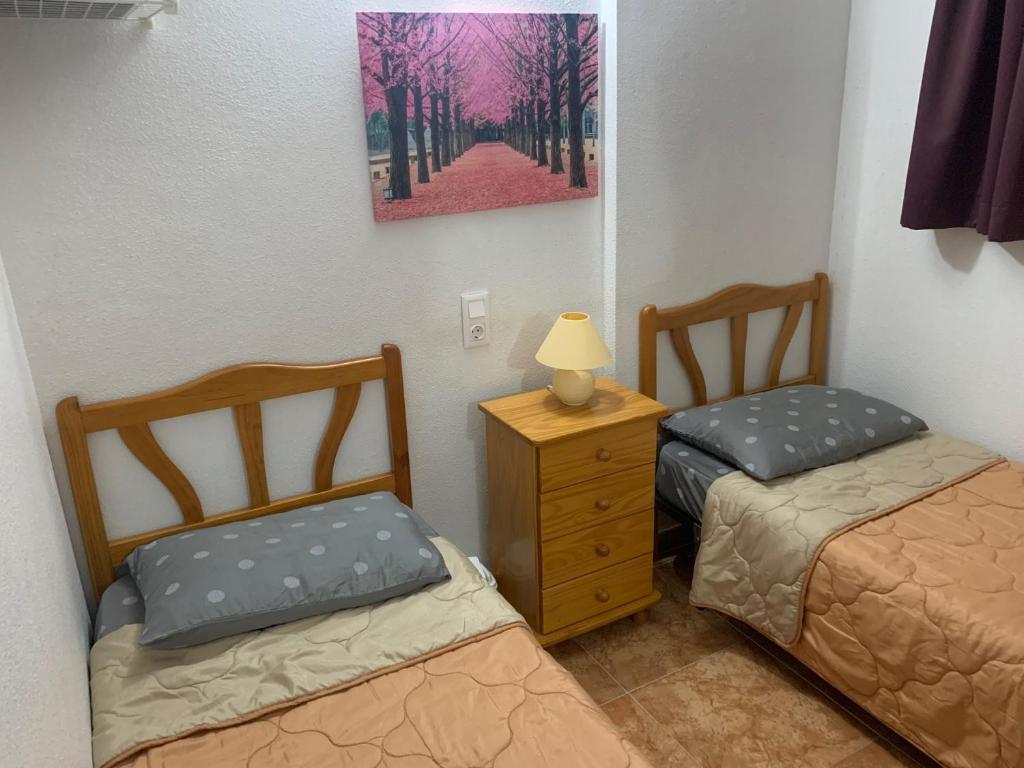 um quarto com 2 camas e um candeeiro numa cómoda em Relax, mar y sol em Torrevieja