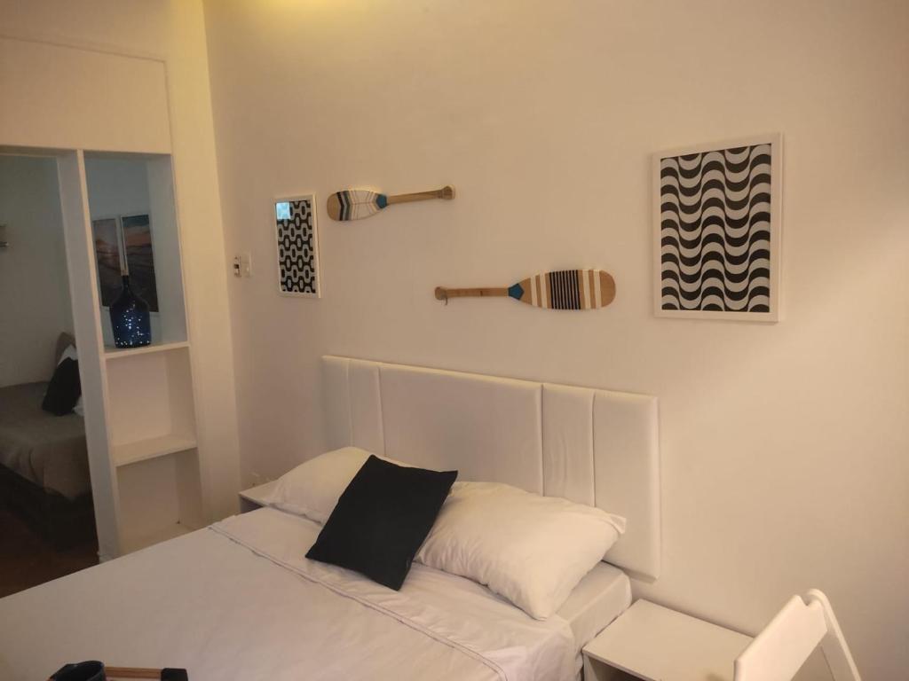 a bedroom with a white bed with a black pillow at Estúdio Centro RJ Pequena África in Rio de Janeiro