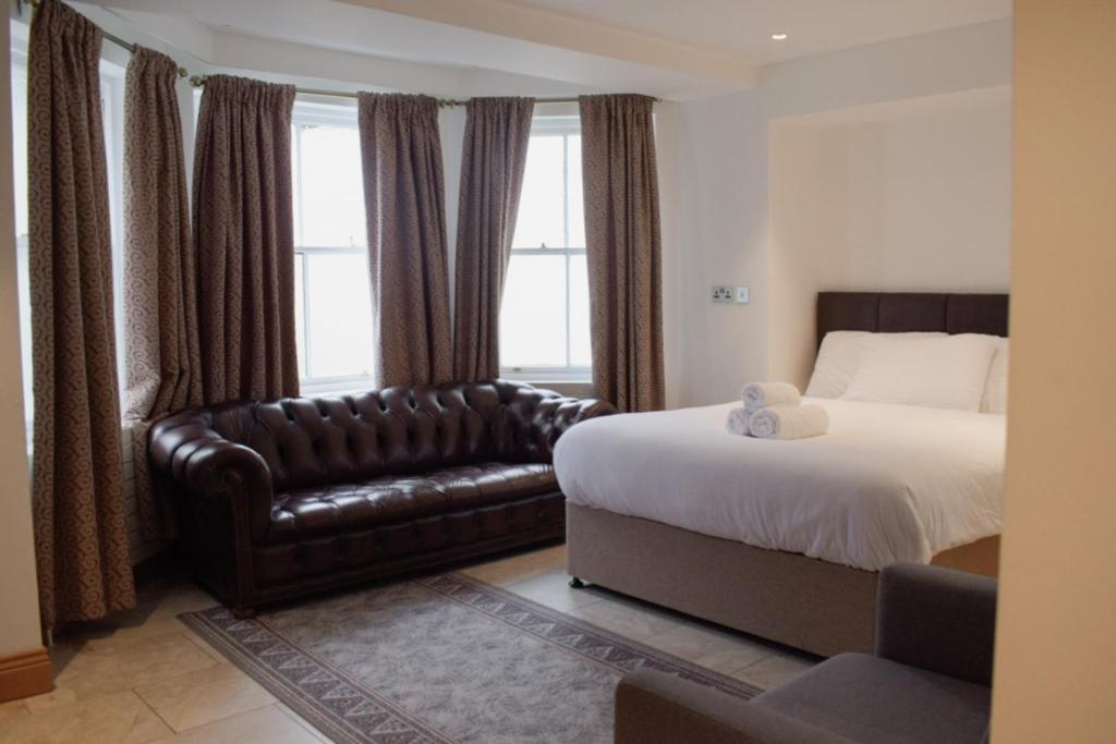 um quarto de hotel com uma cama e um sofá de couro em Osborne Aparthotel em Eastbourne