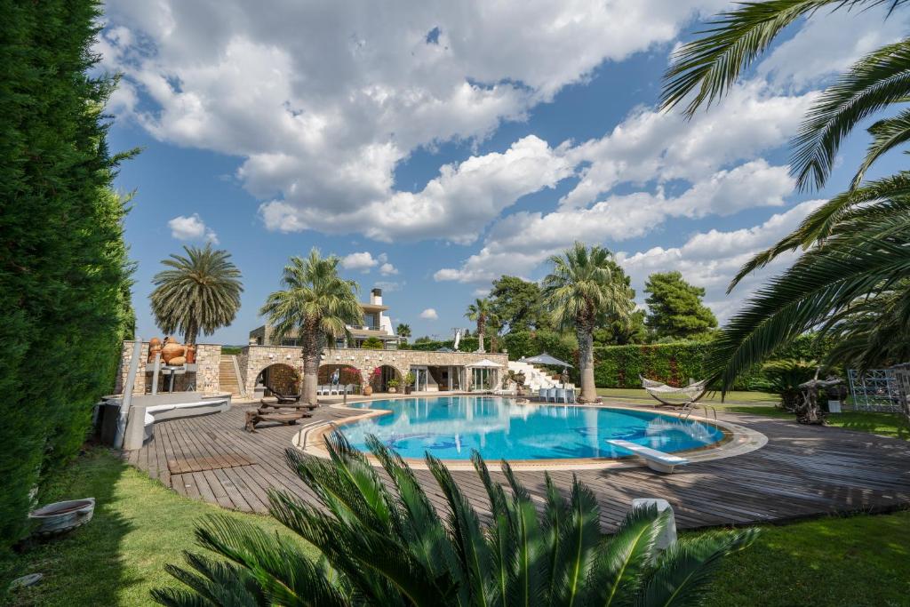 a swimming pool with palm trees and a house at Empyrean Villa in Kalyves Poligirou