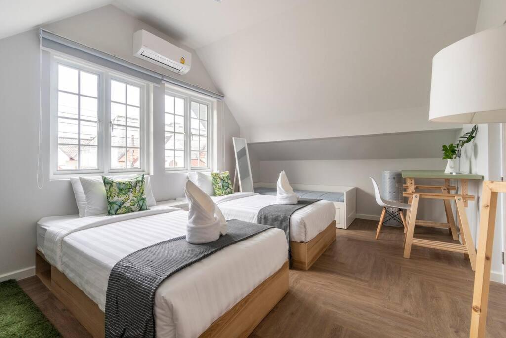 two beds in a room with a desk and a table at Naka Cozy House in Phuket City in Ban Rangeng