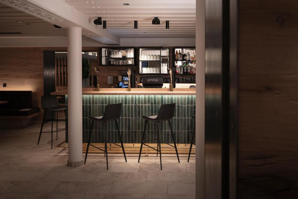 a bar in a restaurant with four stools at Hotel Gamshag in Saalbach-Hinterglemm