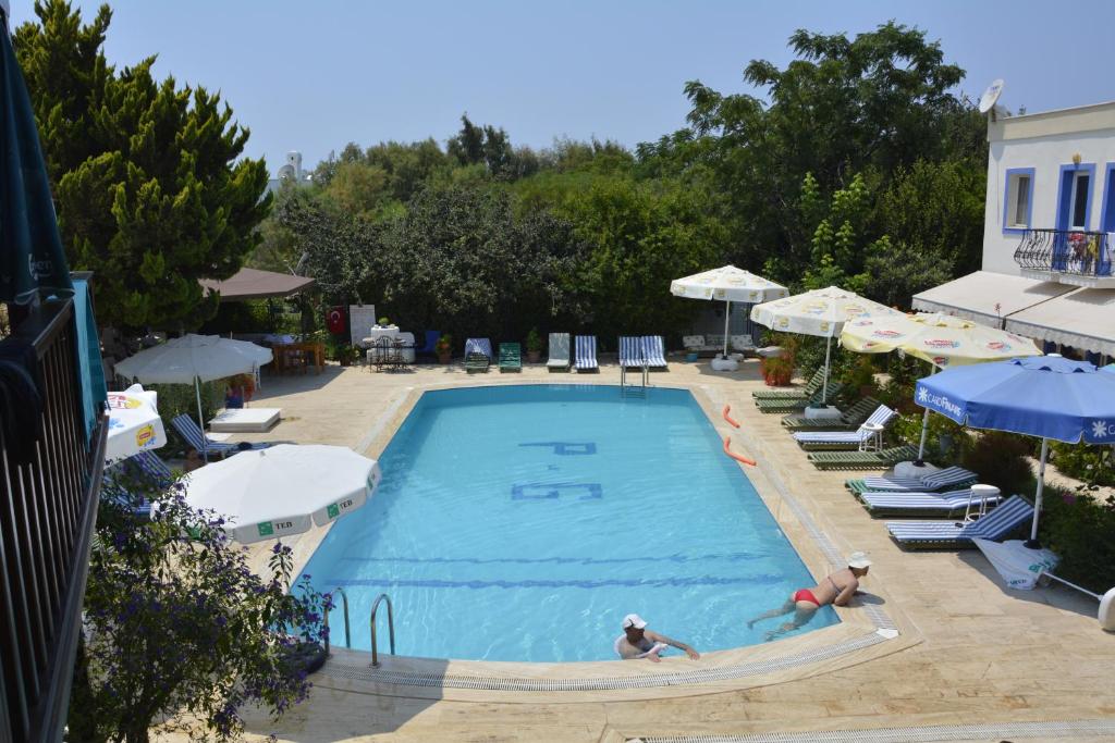 two people swimming in a swimming pool with umbrellas at Paradise Garden Apartments in Gümüşlük