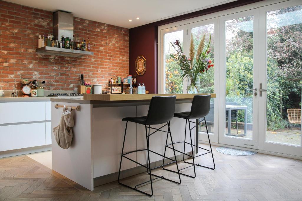 a kitchen with a counter and two stools at a bar at Spacious apartment with garden in Amsterdam