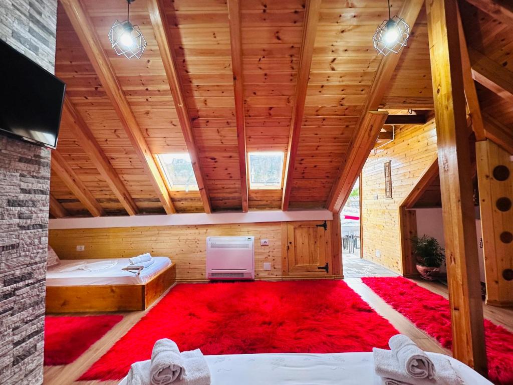 um quarto no sótão com 2 camas e um tapete vermelho em Kore Guest House em Gjirokastër