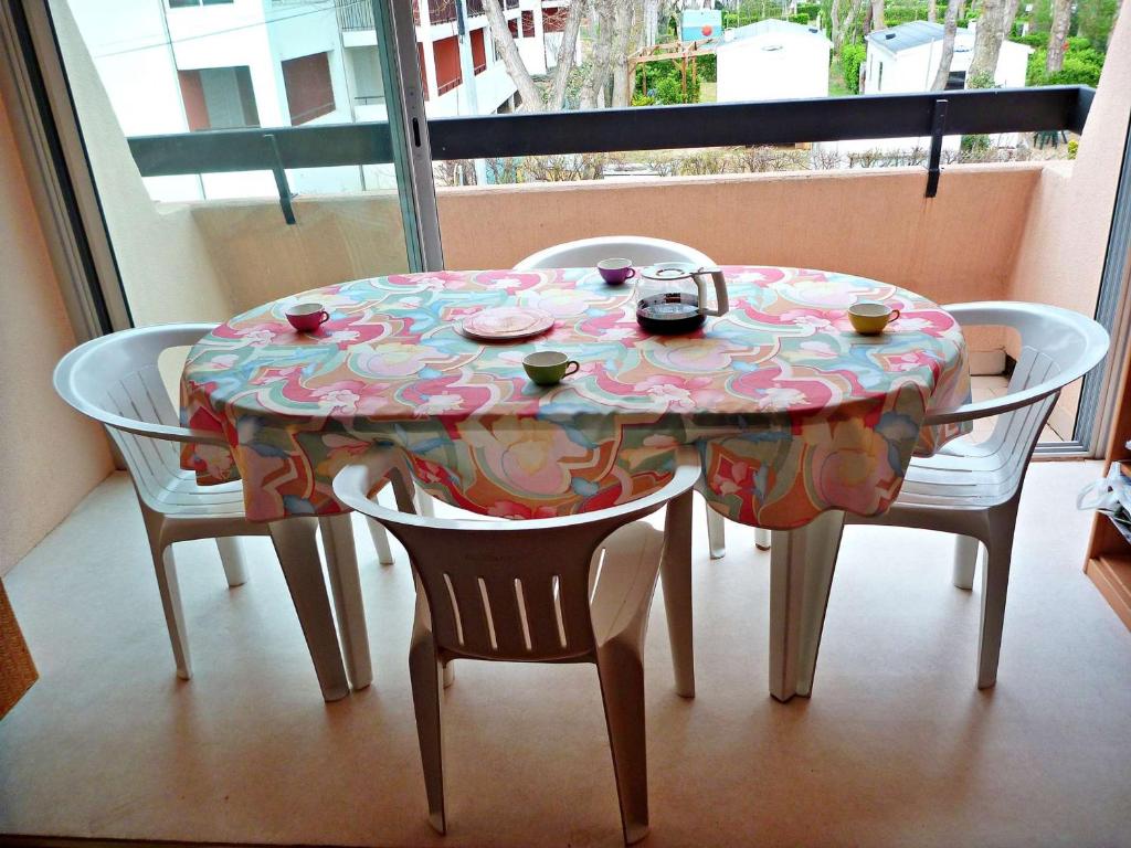 une table avec un tissu de table fleuri et 2 chaises dans l'établissement Appartement cosy avec accès plage et parking, 4 couchages à Marseillan-Plage - FR-1-387-92, à Marseillan