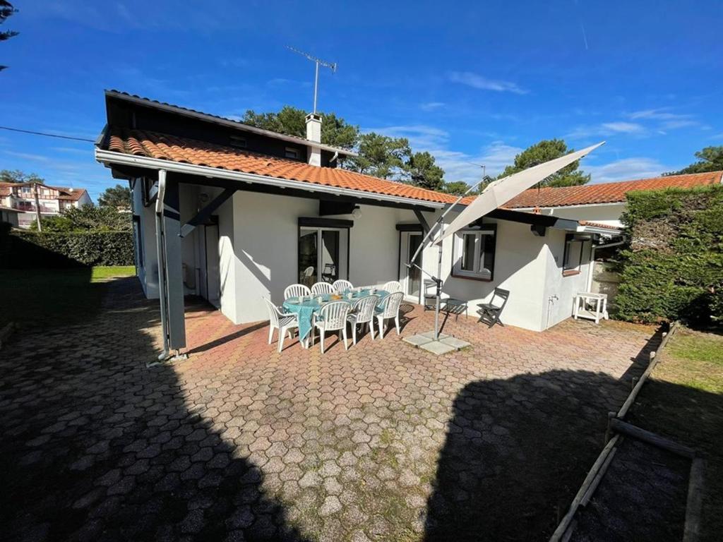 une maison avec un patio avec une table et des chaises dans l'établissement Maison Familiale Près de la Plage avec Grand Jardin et Parking Privé - FR-1-413-108, à Capbreton