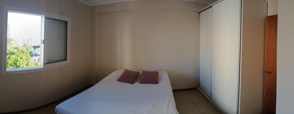 een kleine slaapkamer met een wit bed en een raam bij Dpto. zona sur - Ubicación ideal in Santa Fe