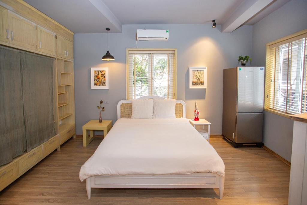 a bedroom with a white bed and a refrigerator at Chez Van in Hanoi