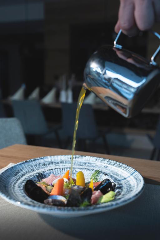 a person is pouring sauce onto a plate of food at Hotel Gamshag in Saalbach-Hinterglemm