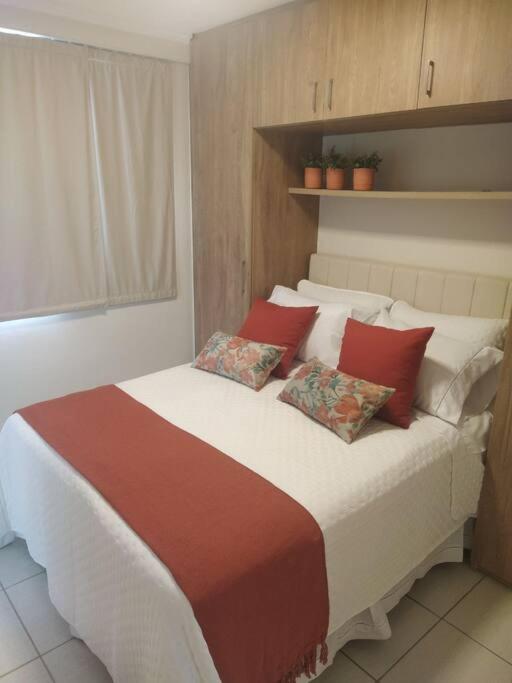 a bedroom with a large bed with red pillows at Apartamento Aconchegante in Brasília