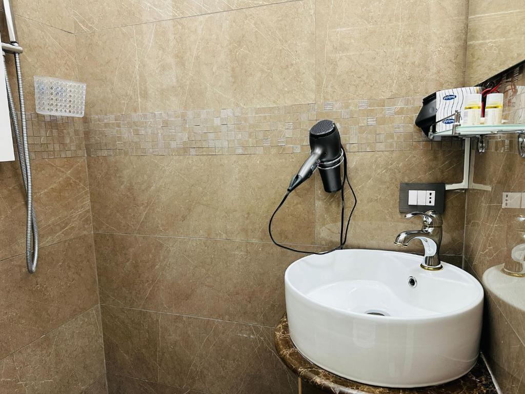 bagno con lavandino e telefono appeso al muro di Rosa Italia Hotel Roma a Roma