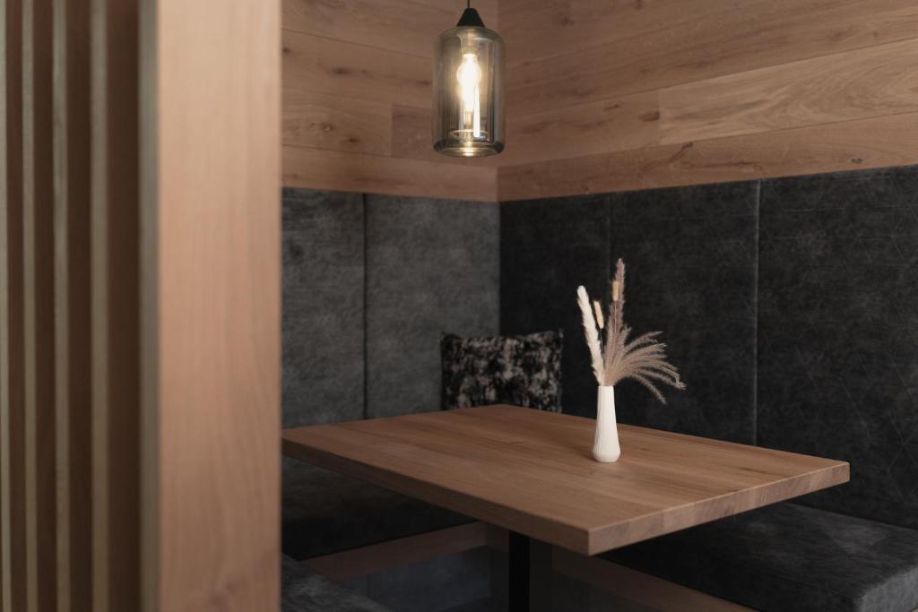 a wooden table with a vase of flowers on it at Hotel Gamshag in Saalbach-Hinterglemm