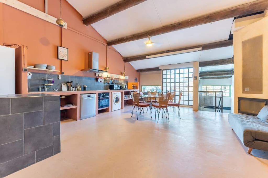- une grande cuisine avec des murs orange, une table et des chaises dans l'établissement Loft de 150m2 avec terrasse, à Marseille