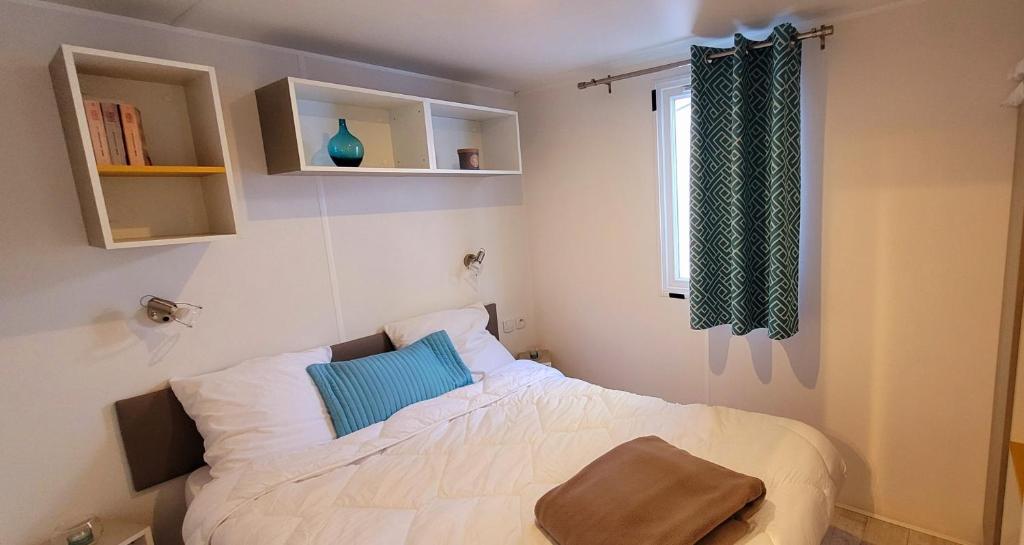 a bedroom with a white bed with a blue pillow at Camping Aux Portes De Cassis in La Bédoule
