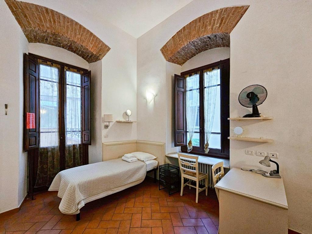 um quarto com uma cama, uma secretária e janelas em Confortevole App Centro Storico em Florença