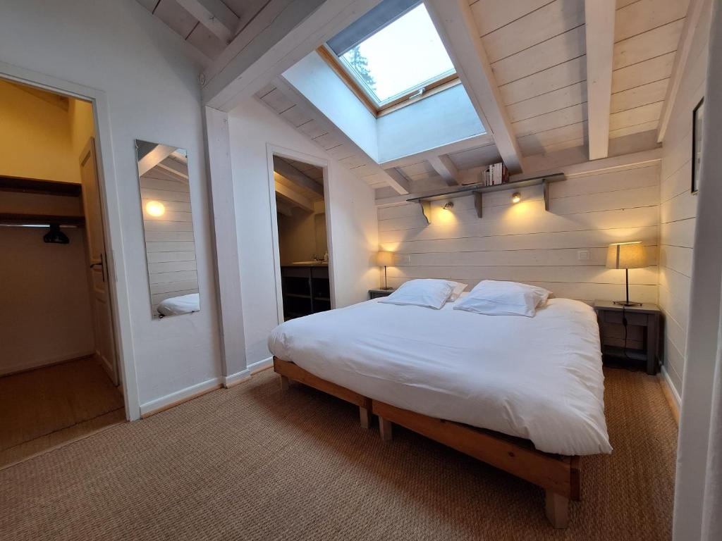 a bedroom with a large white bed with a skylight at Le Chalet des Grands Montets 2 in Chamonix