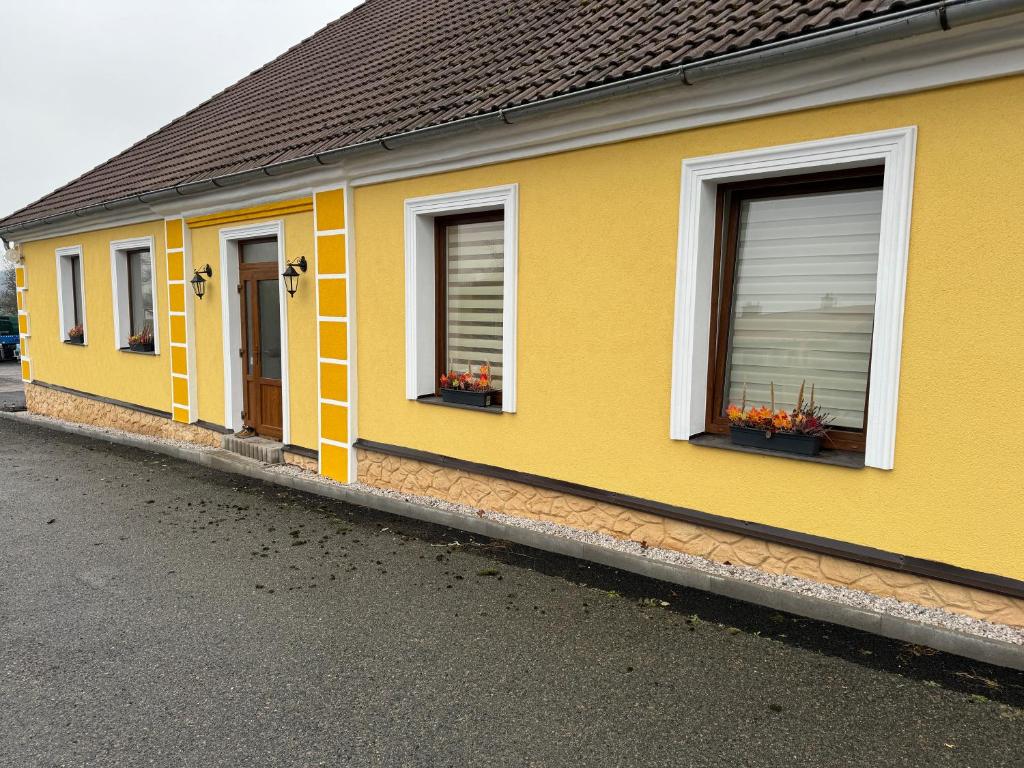 un edificio amarillo con ventanas y flores en el lateral en Apartmán Alfa, 