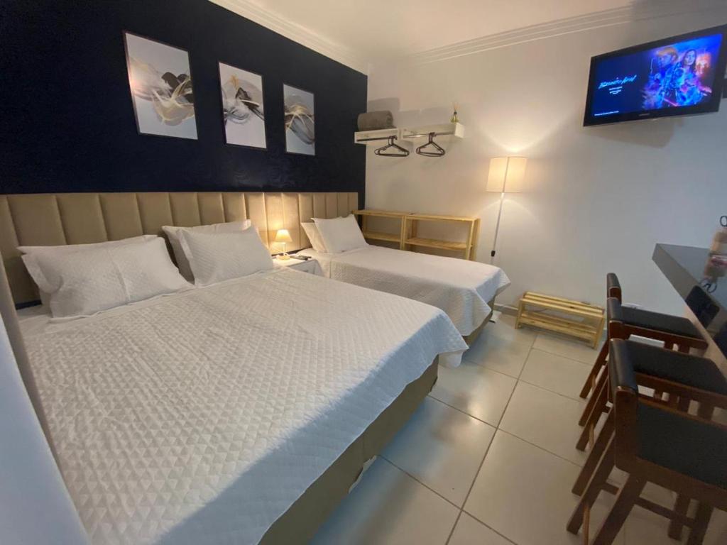 pokój hotelowy z 2 łóżkami i telewizorem z płaskim ekranem w obiekcie Suíte Studio 1 Enseada Tortuga Mobiliada w mieście Guarujá