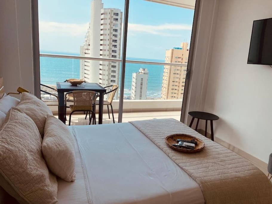 Schlafzimmer mit einem Bett und einem großen Fenster mit einem Tisch in der Unterkunft !Nuevo, Lujoso y vista al mar ! in Cartagena de Indias