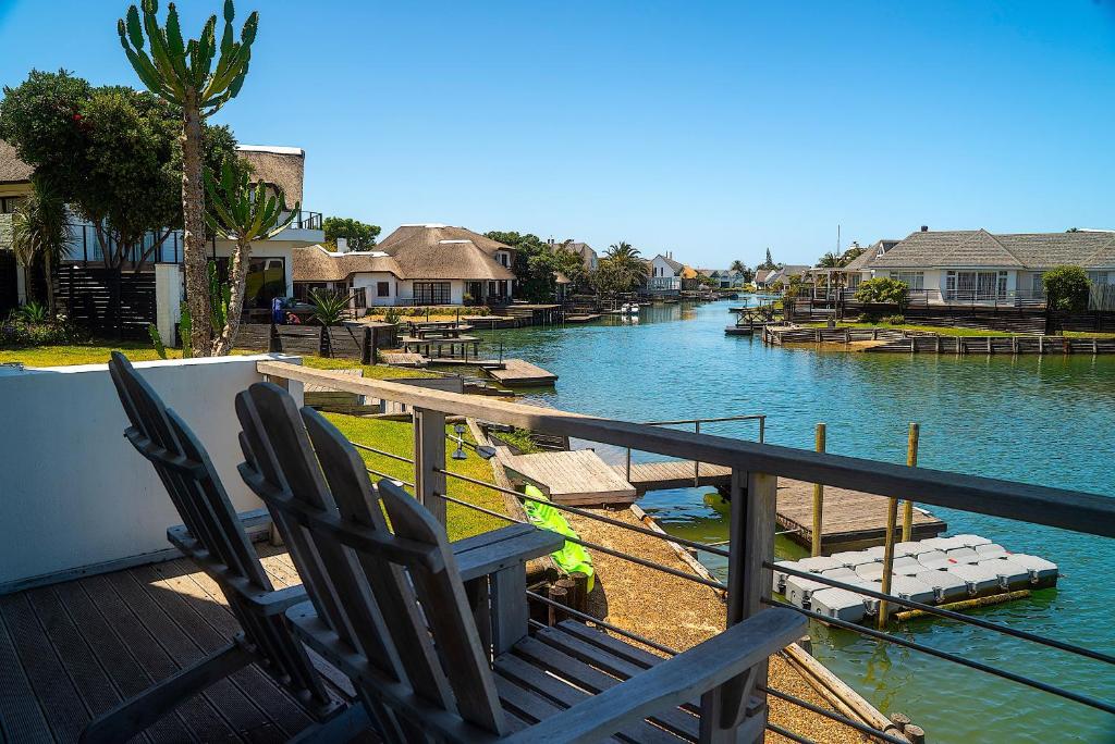 two chairs sitting on a deck overlooking a river at CANAL GUEST HOUSE - Waterfront Accommodation in St Francis Bay