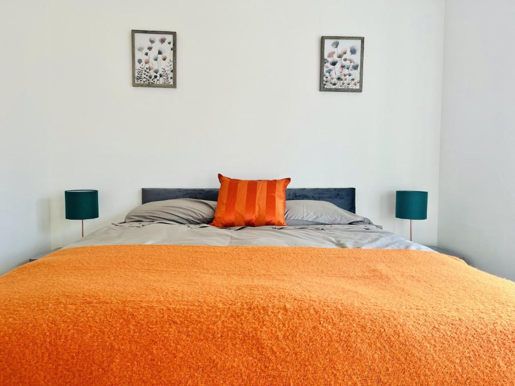Impeccable 3-Bed House in Nottingham في نوتينغهام: غرفة نوم بسرير وبطانية برتقالية ومصباحين