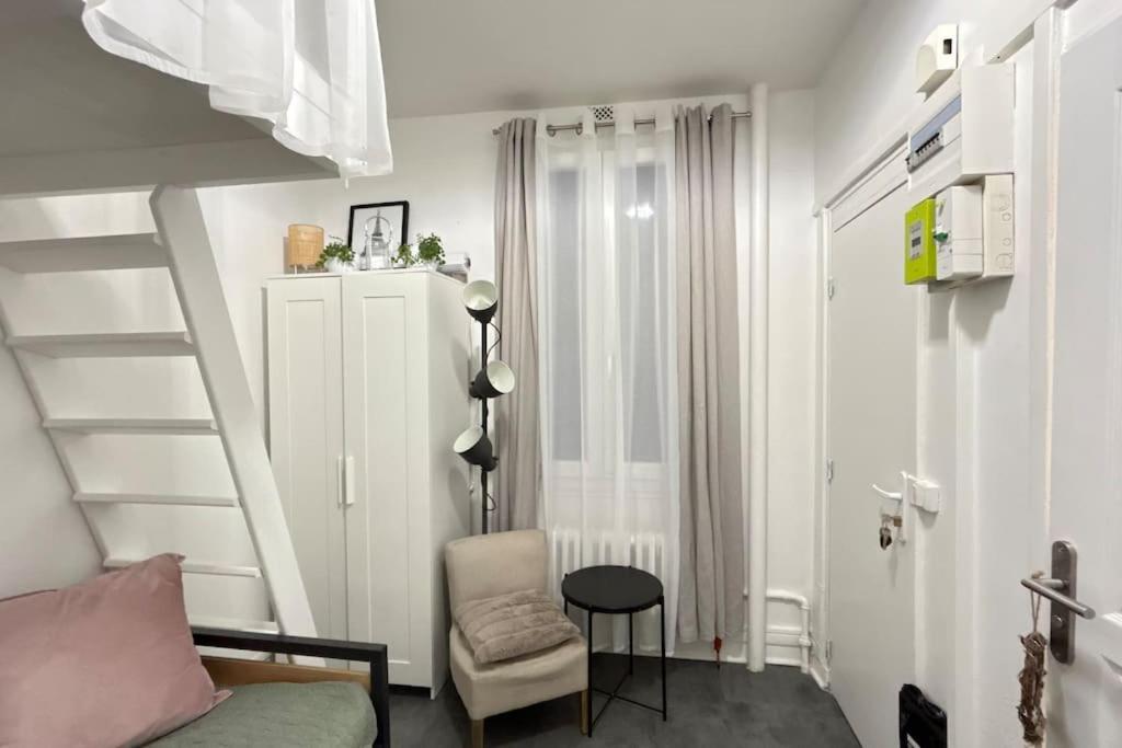 Cette chambre blanche dispose d'un escalier et d'une chaise. dans l'établissement Cozy studio in Paris 15eme, à Paris