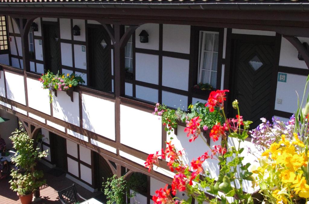 a building with black and white windows and flowers at Landhotel &amp; Restaurant Kains Hof in Uhlstädt