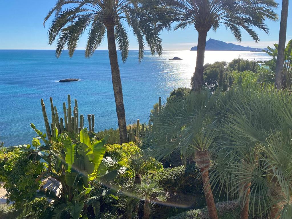 vistas a una playa con palmeras y al océano en El jardin Botánico Villa LUZ, en Altea