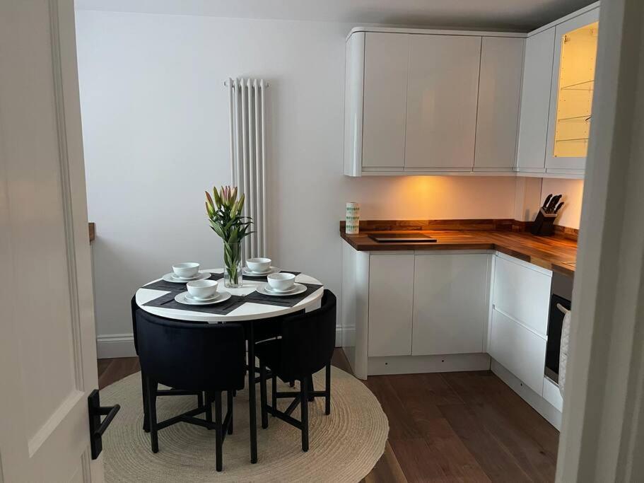 a kitchen with a small table with chairs and a counter at Newly refurbished apartment, near station & river in London