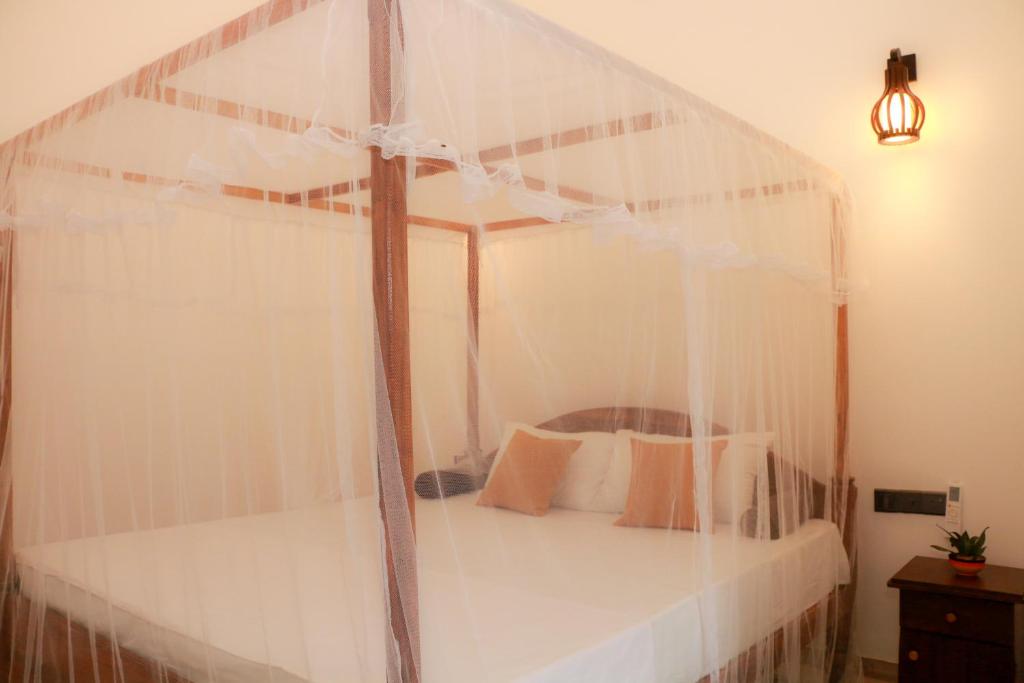 a white canopy bed with white pillows in a room at Simplex Sea Place in Tangalle