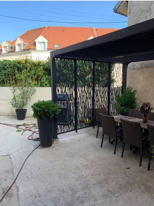 d'une terrasse avec une table, des chaises et un auvent noir. dans l'établissement La campagne à 30 min de Paris !, à Dammartin-en-Goële