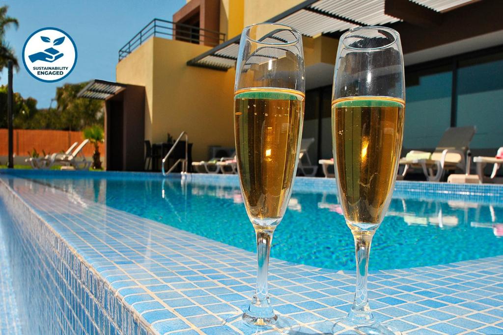 two glasses of champagne sitting next to a swimming pool at Villa Bahamas by Algarve Vacation in Armação de Pêra