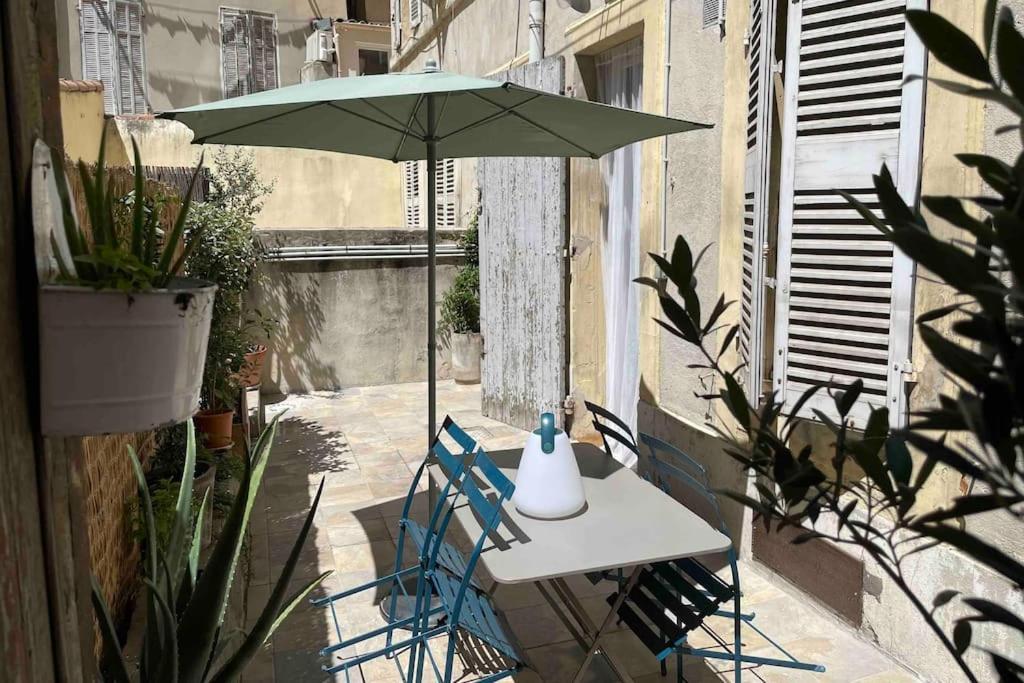 une table et des chaises avec un parasol sur une terrasse dans l'établissement Marseille Côté Cour, à Marseille