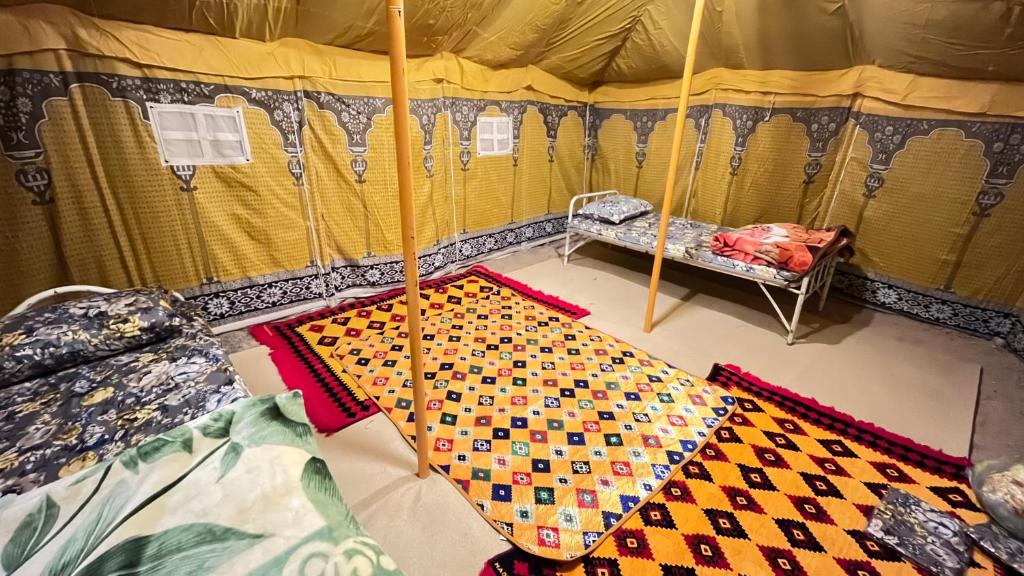 a tent with a bed and an umbrella in it at مزرعة القمة in Mogayra