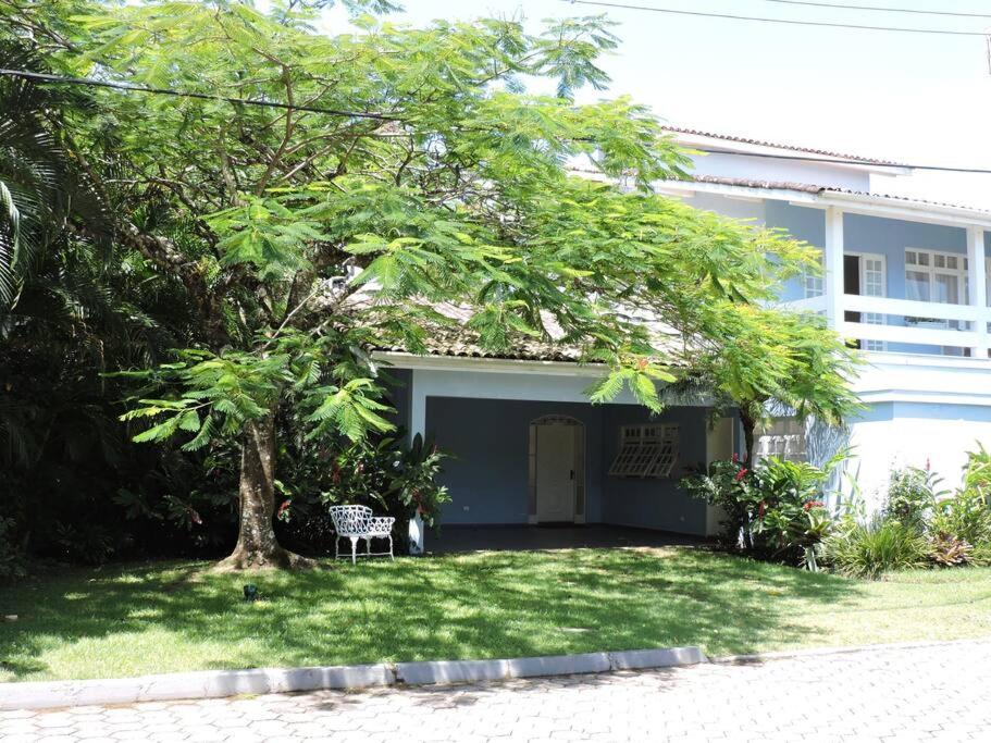 une maison blanche avec un arbre dans la cour dans l'établissement Maresias, à São Sebastião