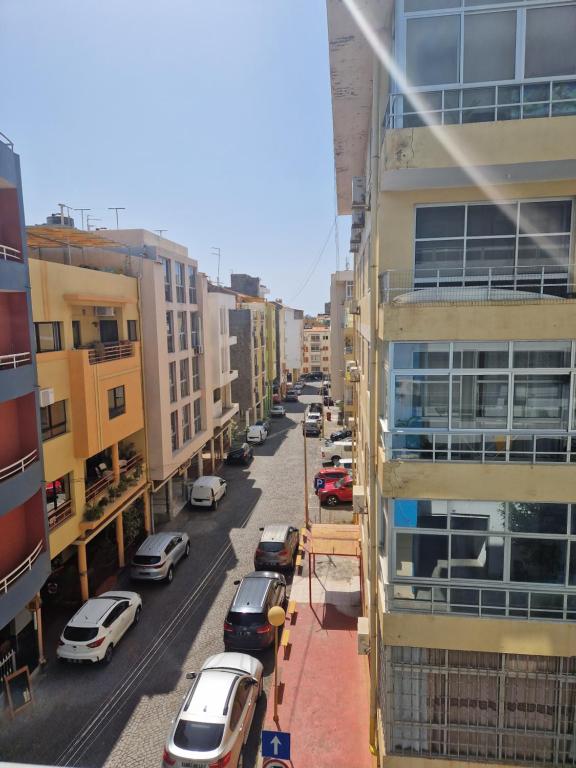 une rue de la ville avec des voitures garées à côté des bâtiments dans l'établissement Condomínio palma azul II, à Praia