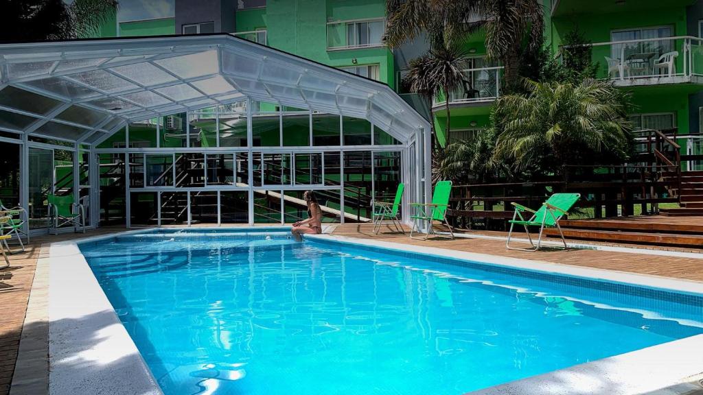 a swimming pool with a canopy and chairs next to a building at Oasis Apart-Spa in Las Gaviotas