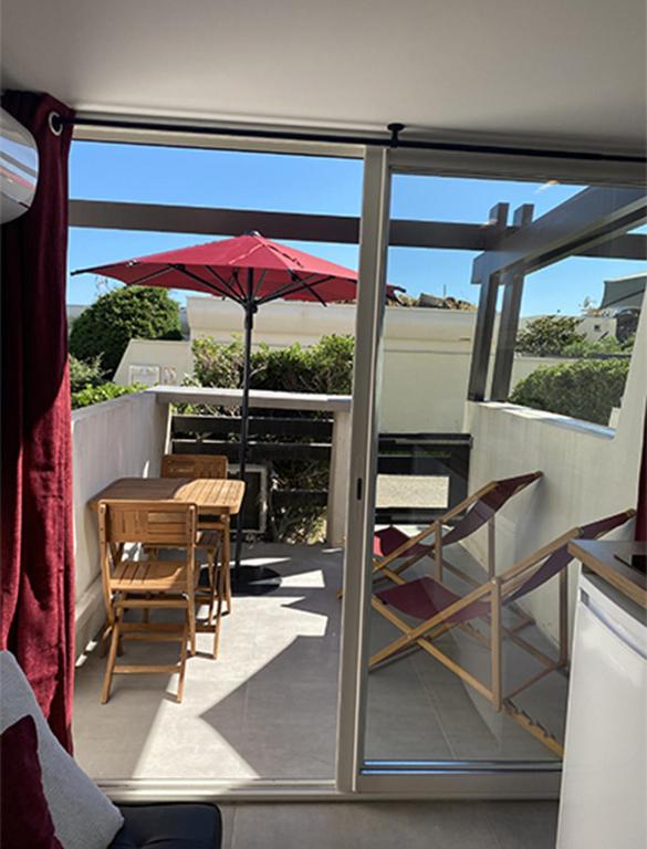 een balkon met een tafel en stoelen en een parasol bij Cap d'Agde Naturiste Port Nature 2 in Cap d'Agde