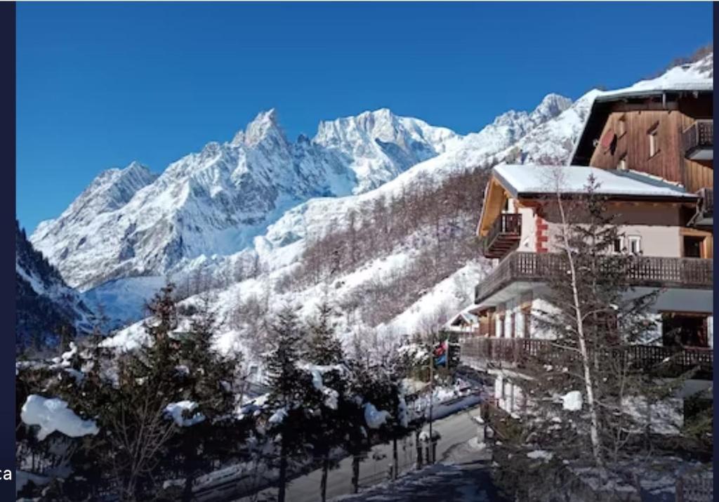 budynek z pokrytymi śniegiem górami w tle w obiekcie Hotel Astoria w mieście Courmayeur