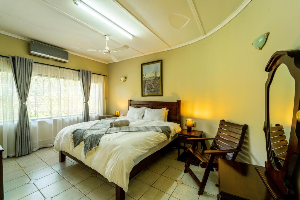 a bedroom with a bed and a table and a window at Room in Villa - Zambezi Family Lodge - Lion Room in Victoria Falls